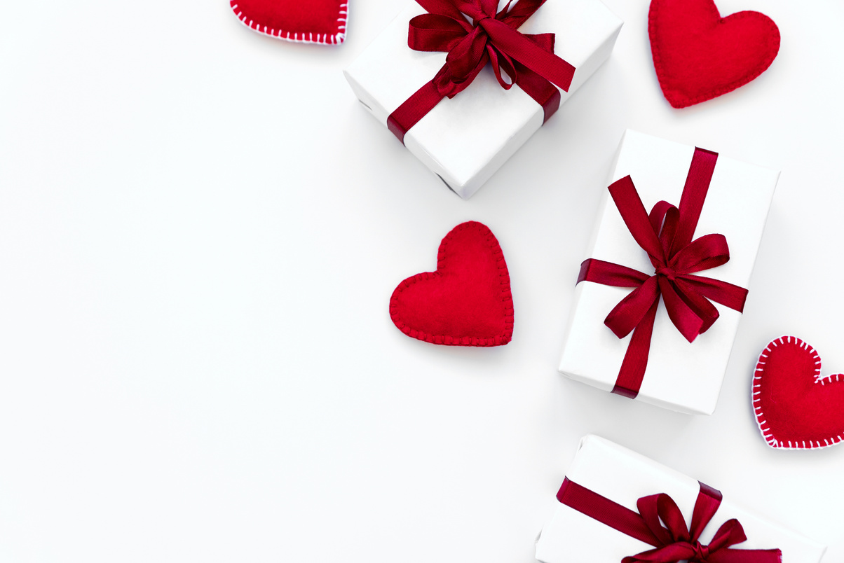 Border from gift boxes wrapped red ribbon with felt hearts on white background. Valentines day or Woman's day holidays concept. Top view.